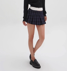 Detailed view of dark plaid pleated mini skirt with precise tailoring and retro style
