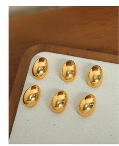 Macro view of six gold-plated teardrop stud earrings with a polished mirror finish