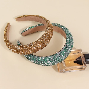 Close-up of sparkling rhinestone and pearl headbands in gold and green with velvet lining