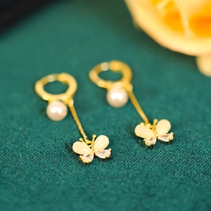 Macro detail of golden butterfly tassel earrings with shell texture and sparkling crystals