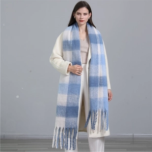 Détail d'une écharpe à carreaux bleus et blancs avec franges sur un manteau blanc