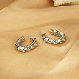 Détail de boucles d'oreilles en U argentées texture lave et cristaux sur de la soie