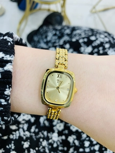Detail of luxury gold square watch with diamond markers on a female wrist