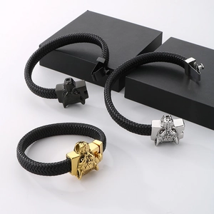 Braided leather wolf head bracelets in black, silver and gold tones on geometric blocks