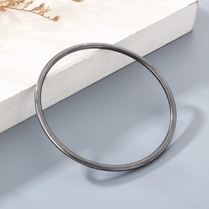 Detail of 3mm minimalist matte black titanium steel bangle on white geometric stand