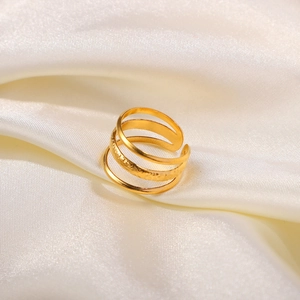Close-up of golden multi-layer triple line open ring on elegant cream silk fabric