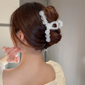 Détail d'une grande pince à cheveux florale irisée sur un chignon bas élégant pour femme