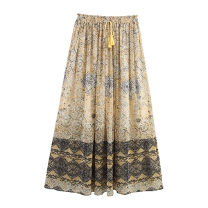 Detail of bohemian maxi skirt with yellow floral print and waist tassel drawstring tie