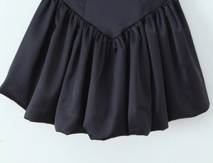 Détail de la jupe bouffante en satin noir avec taille en V et texture plissée