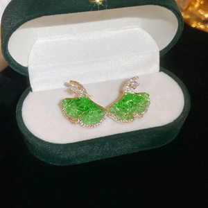Detailed view of ginkgo leaf earrings with green crystals in a velvet jewelry box