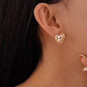Detailed view of elegant gold heart earrings with white cubic zirconia on model