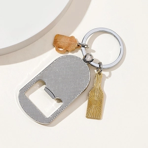 Detail of metal keychain bottle opener with beer mug and bottle charms on white background