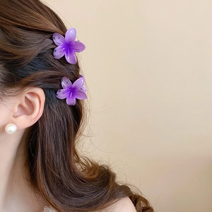 Detail of purple gradient sunflower hair claws and pearl earring worn by a model