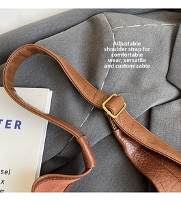 Détail de la bandoulière réglable en cuir marron avec boucle dorée pour sac seau