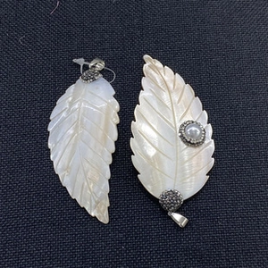 Detailed view of white mother of pearl leaf pendants with pearl and diamond accents
