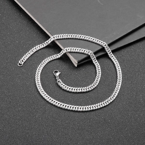 Overhead view of a polished silver stainless steel Cuban link chain on a dark background