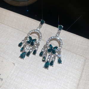 Dettaglio orecchini in argento con pietre verdi scure e nappe di strass brillanti