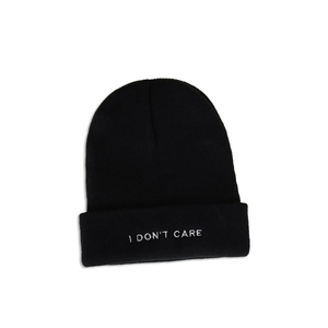 Detail shot of the white I DON'T CARE embroidery on a black ribbed knit beanie hat