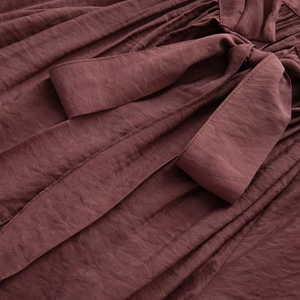 Close-up of deep brown tie-neck detail on elegant textured sheer blouse for women