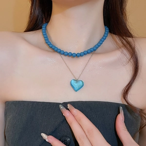 Detail of layered necklace featuring blue beads and a translucent heart pendant