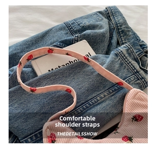 Detail of pink corduroy shoulder bag with strawberry embroidery and wide strap