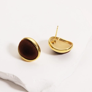 Detail view of oval velvet earrings with gold plated frame and matte brown flocking finish