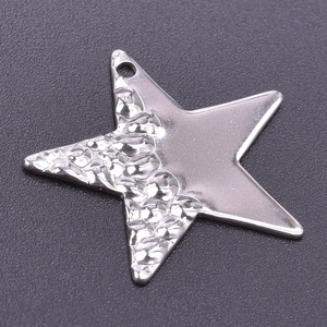 Détail macro du pendentif étoile avec textures contrastées en acier martelé et poli