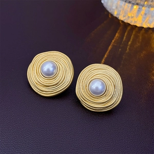 Detail shot of vintage spiral metal earrings with center pearl on leather surface