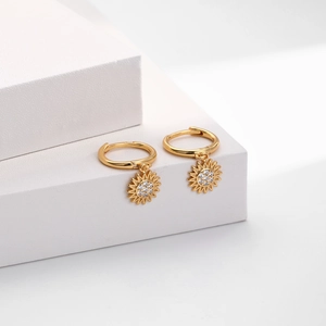 Macro detail of gold flower earrings with pavé zircon stones on white display