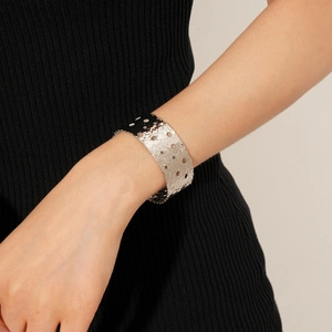 Detailed macro view of wide silver hammered texture cuff bracelet with hollow circle design
