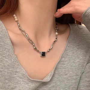 Detail of asymmetric pearl and silver chain necklace featuring a square black gemstone pendant