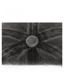 Macro detail of the stitched crown and top button on a black washed cotton baseball cap