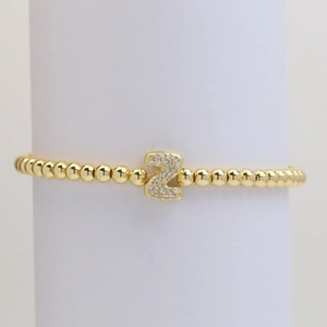 Macro detail of gold bubble bead bracelet featuring a luxury zircon paved letter Z charm