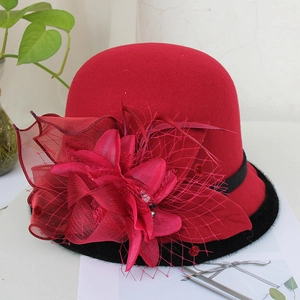 Detail of red wool felt pillbox hat with large mesh flower, feathers and fur trim