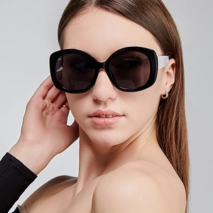 Fashionable oversized oval sunglasses with black frames and white temples on female model