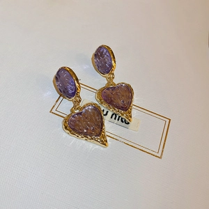 Close-up of vintage heart drop earrings featuring purple resin and gold-tone metal frame