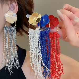 Macro detail of floral tassel earrings showing colorful painted petals and beaded fringe