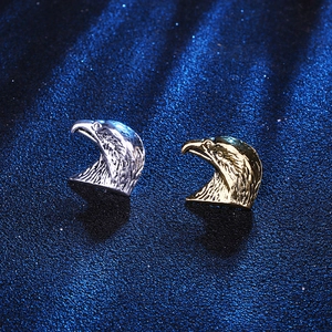 Detailed view of eagle head stud earrings in polished gold and silver metal finishes