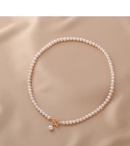 Detail of elegant freshwater pearl necklace with gold OT toggle clasp on beige silk