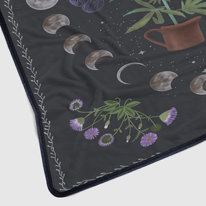 Close-up of soft flannel blanket with celestial moon phases and floral illustrations
