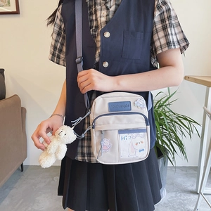 Détail du mini sac à bandoulière en toile porté par un mannequin en décor décontracté