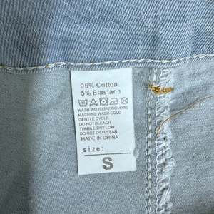 Vista dettagliata dell'etichetta con 95% cotone e taglia S sui pantaloncini in denim