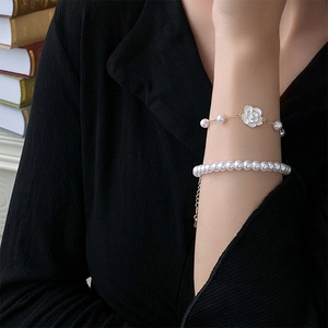 Detailed macro view of French vintage style camellia and pearl stacked bracelet set