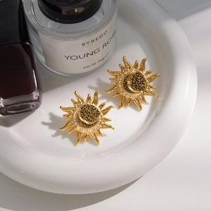 Detail of gold sun and moon earrings with white crystals on a white ceramic plate