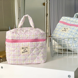Close-up of quilted cotton makeup bags in pink and blue with checkered pattern and handles