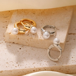 Elegant gold and silver pearl hoop earrings on minimalist stone and silk background