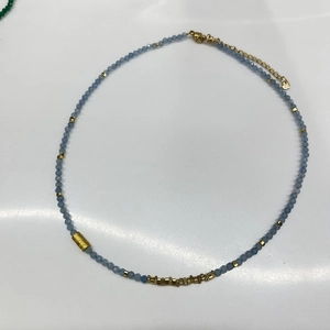 Detail of greyish-blue beaded necklace with gold metal spacers and lobster clasp
