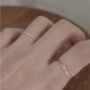 Close-up of minimalist silver twisted rope and knot ring set on model hand