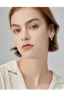 Elegant woman wearing silver moissanite hoop earrings and a delicate rose gold necklace