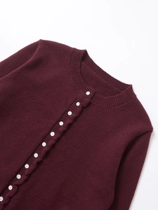 Detailed view of dark red knit cardigan showing white buttons and fine fabric texture